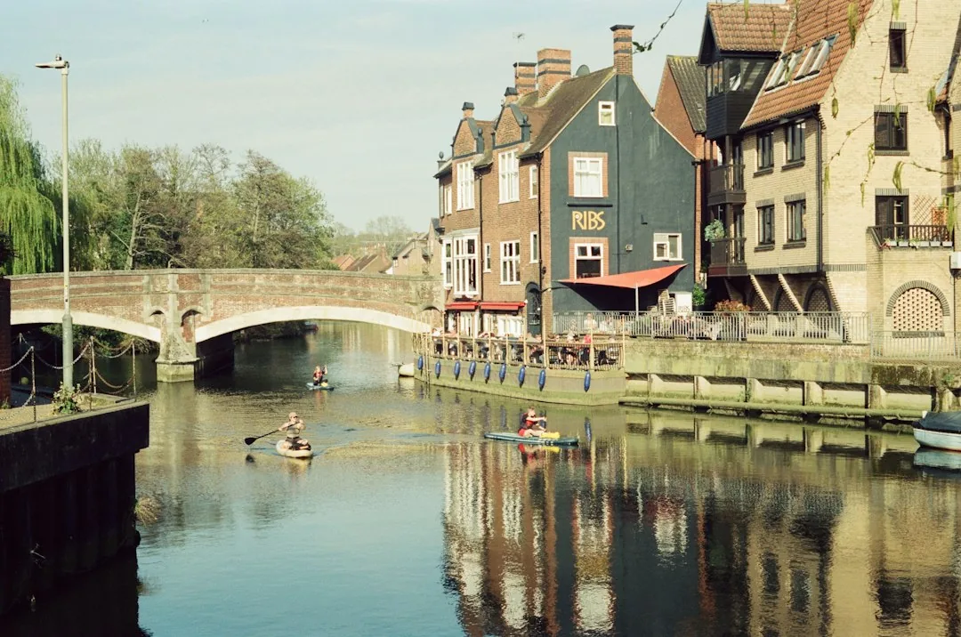 Norwich — Kayakers on a river with old buildings and a bridge