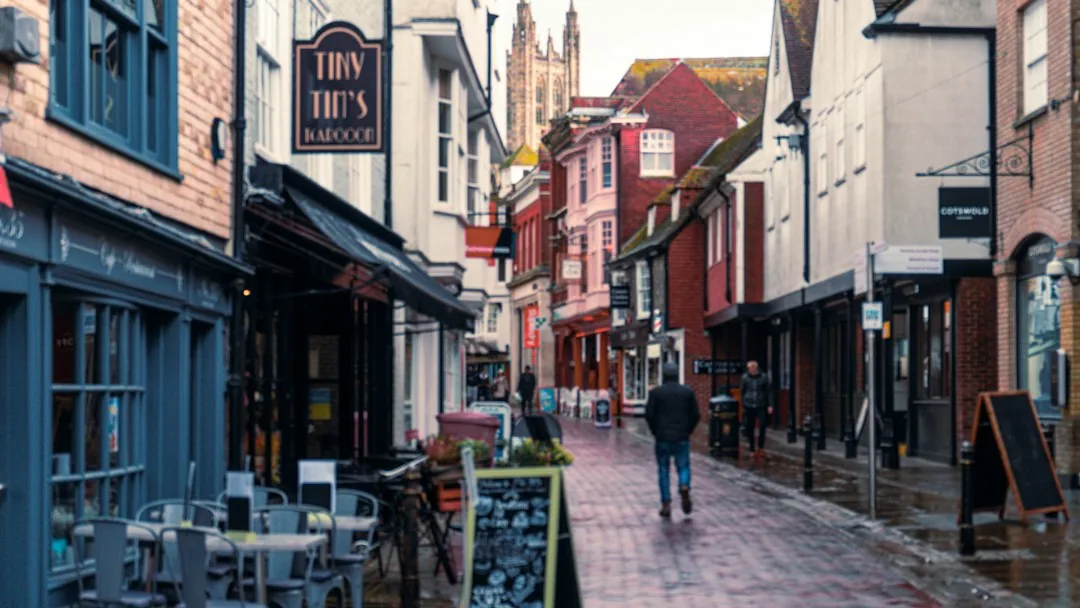 Canterbury — a man walking down a street next to tall buildings
